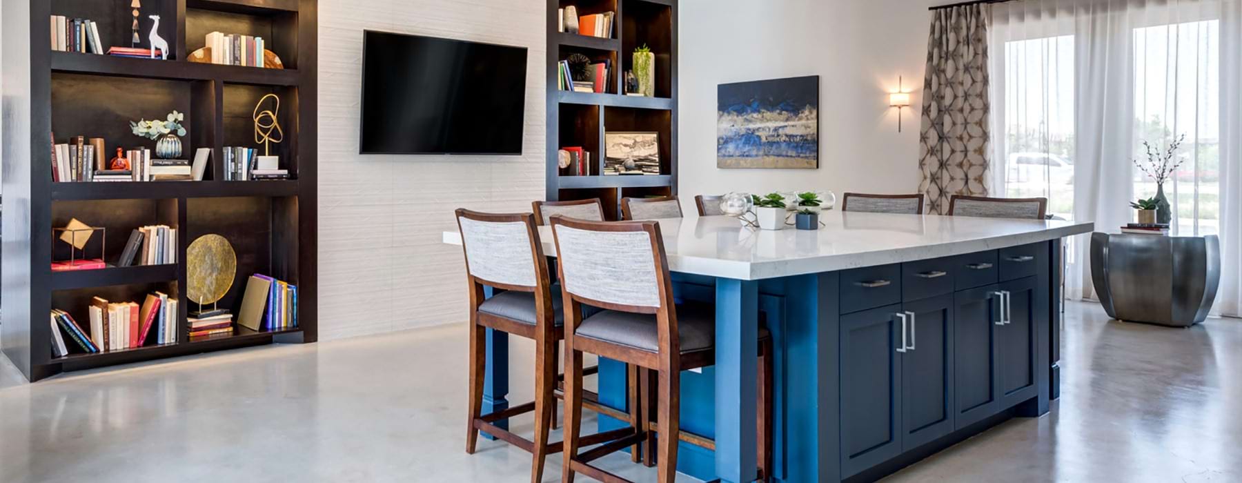 Clubhouse island table with pub style seating, hanging TV and bookshelves.